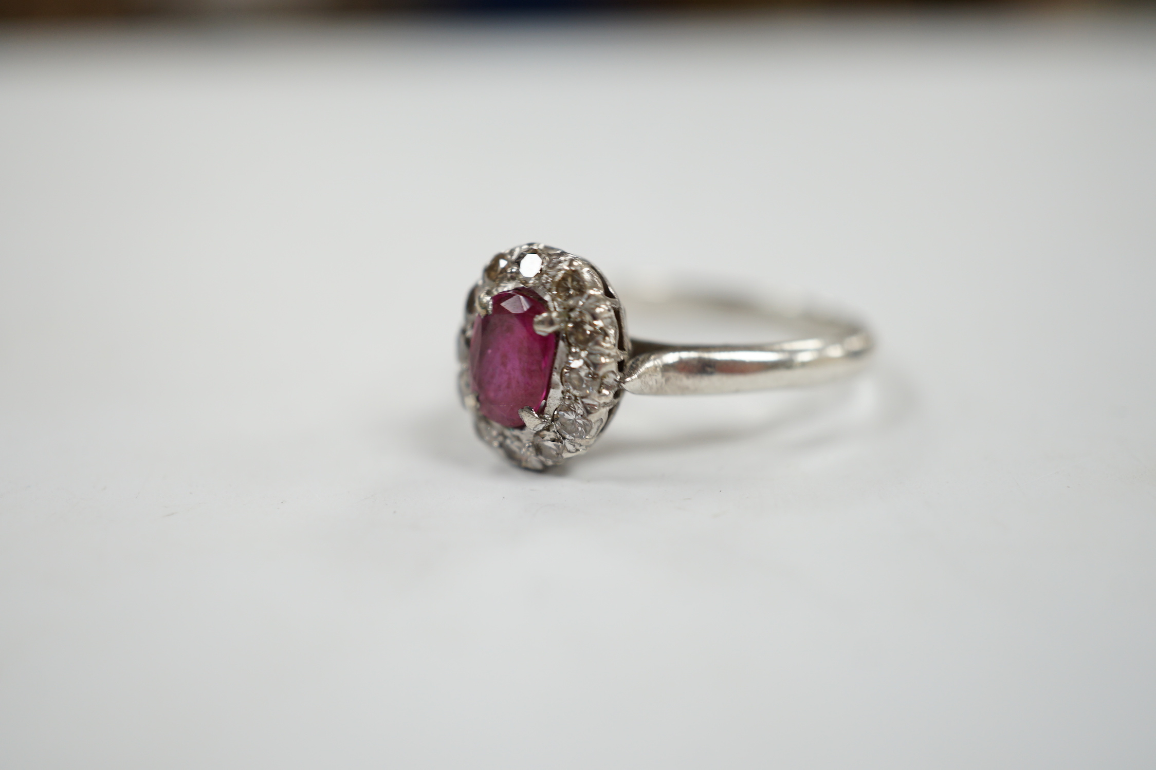 A white metal, synthetic? ruby and diamond set oval cluster ring, size P, gross weight 3.3 grams.